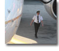 Photo of a commercial pilot walking under a large jet parked at the gate