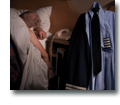 Photo of a commercial pilot wearing uniform with epaulettes and hat half sitting idly, resting or sleeping