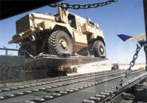 Military vehicle being loaded as cargo on an airplane.